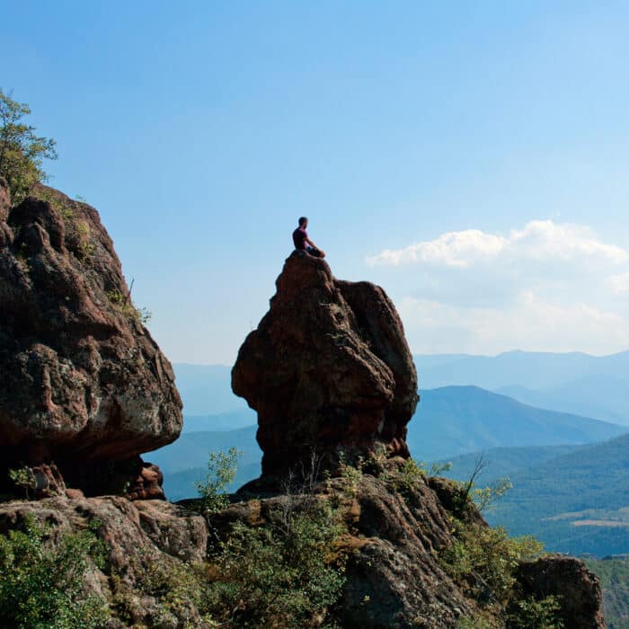 Guy meditating near a rock cliff